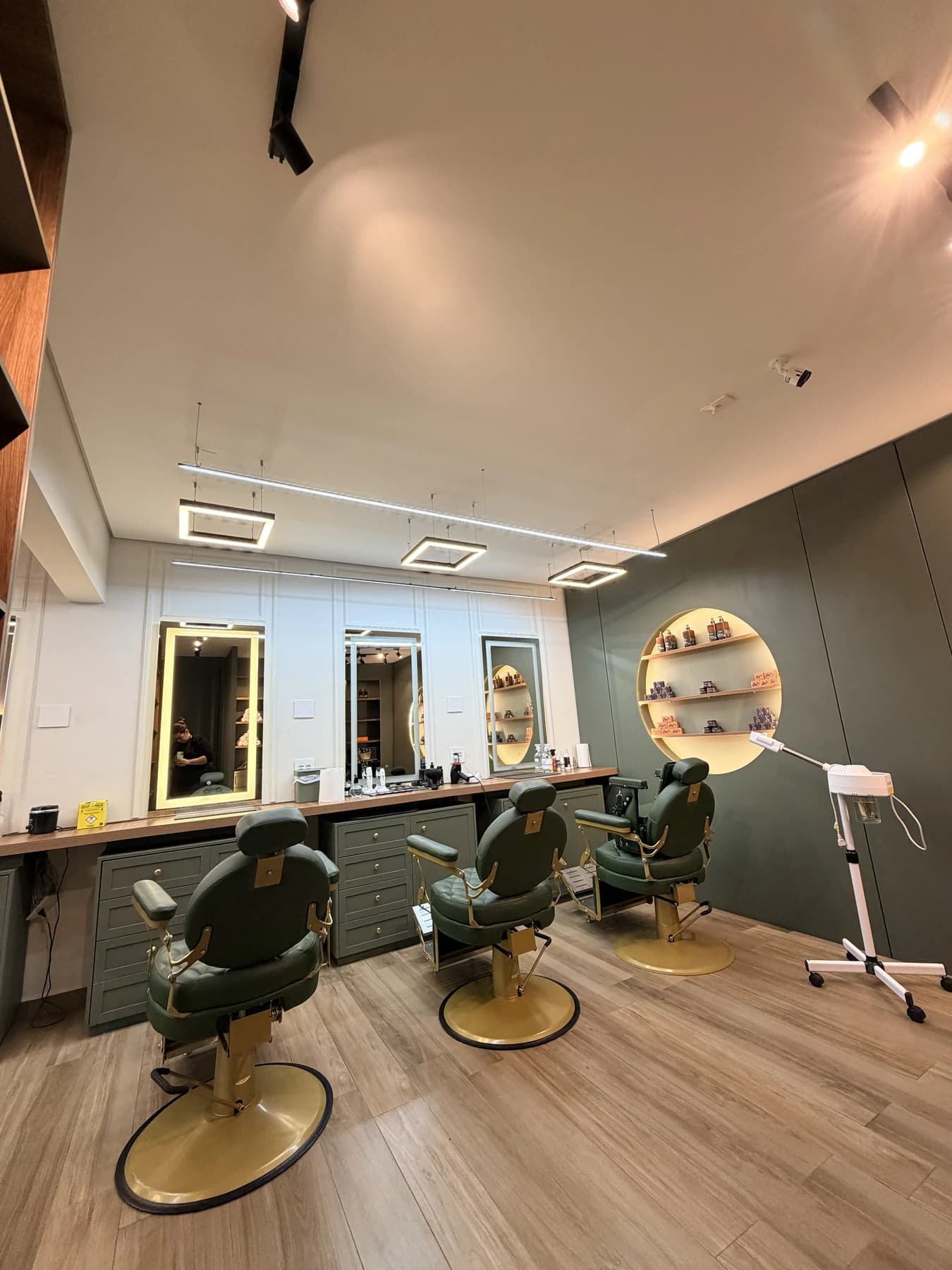Estrutura do salão com cadeiras de couro verde e detalhes em ouro